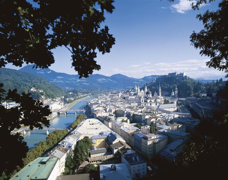 Panorama von Salzburg mit Altstadt und Festung Hohensalzburg, umgeben von Bergen.