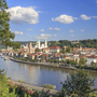 Ansicht von Linz mit der Donau im Vordergrund und Gebäuden im Hintergrund.