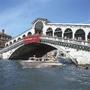 Boot auf Kanal vor der Rialto-Brücke in Venedig bei sonnigem Wetter.