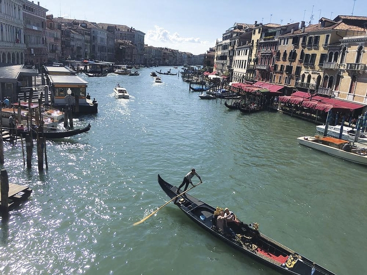 Eine Gondel fährt auf einem Kanal in Venedig bei sonnigem Wetter.