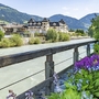 Fluss in Lienz, umgeben von Bergen und Gebäuden, mit Blumen im Vordergrund.