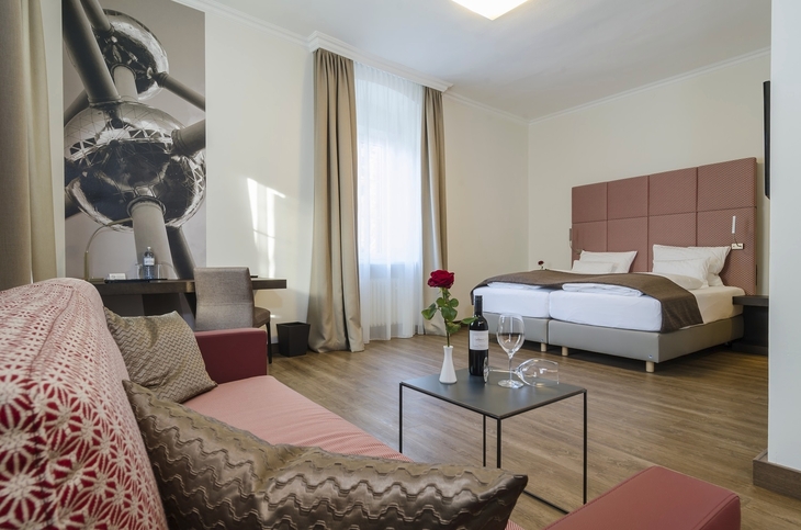 Hotelzimmer mit Doppelbett, Sofa, Tisch und Dekorationen.