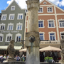 Historischer Brunnen vor bunten Häusern in einer bayerischen Stadt.