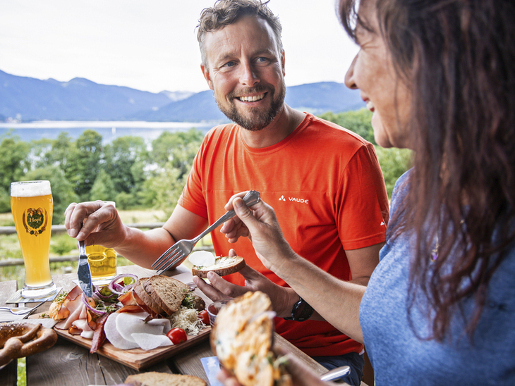 Zwei Personen essen Brotzeit mit Bergblick und Weizenbier im Freien.