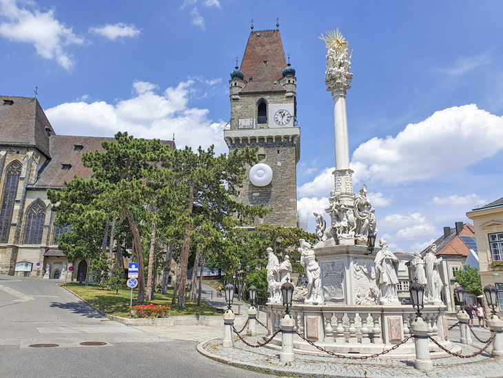 Blick auf den historischen Turm und eine barocke Säule auf dem Platz in Perchtoldsdorf.