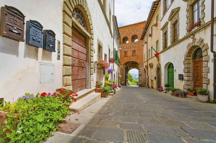 Blick auf ein historisches Stadttor in Montecarlo mit Blumen und alten Gebäuden.
