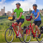 Zwei Radfahrer auf Landstraße mit Blick auf San Gimignano im Hintergrund.