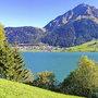 Reschensee mit Dorf am Ufer, umgeben von Bergen und grüner Landschaft.