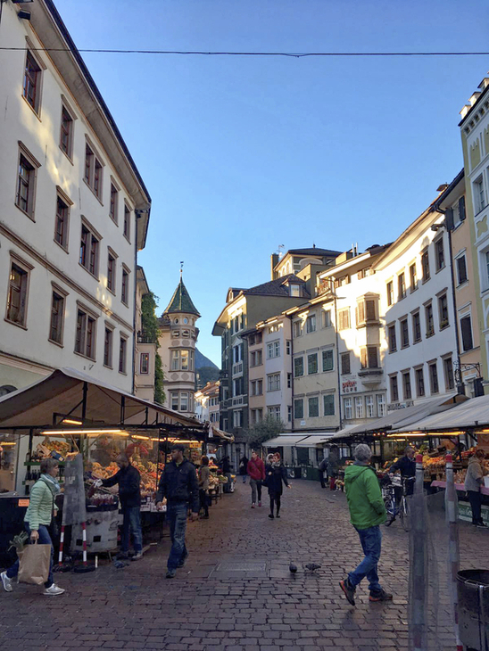 Fußgängerzone in Bozen mit Marktständen und historischer Architektur.