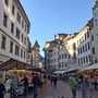 Fußgängerzone in Bozen mit Marktständen und historischer Architektur.