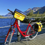 Rotes Fahrrad auf einem Steg am Haidersee mit Bergkulisse im Hintergrund.