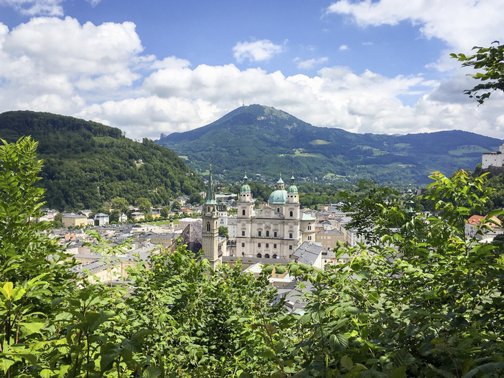 Aussicht auf Salzburg mit grüner Landschaft und Bergen im Hintergrund