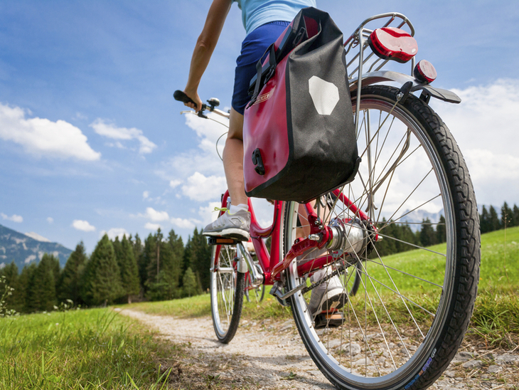 Radfahrer auf einem Feldweg am Chiemsee mit Blick auf Berge im Hintergrund