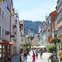 Fußgängerzone in Füssen mit Alpen im Hintergrund bei sonnigem Wetter.