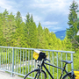 Fahrrad auf einer Brücke am Drau Radweg, umgeben von Wald und Berglandschaft.