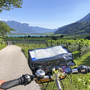 Ein Lenker mit Karte auf einer Radstrecke durch Südtiroler Apfelhaine, Berge im Hintergrund.