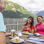 Personen machen eine Radpause am Reschensee mit Blick auf die Berge.