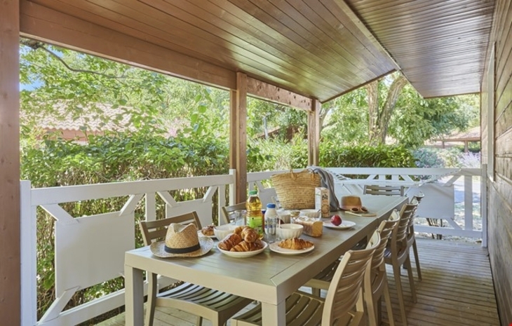 Gedeckter Tisch mit Frühstück auf einer überdachten Terrasse im Grünen.