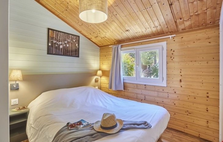 Holzvertäfeltes Schlafzimmer mit Doppelbett und Fenster.
