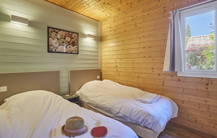 Zwei Einzelbetten in einem Holzvertäfelten Zimmer mit Fenster.