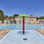 Poolbereich mit Wasserfontäne, umgeben von Liegestühlen und Sonnenschirmen