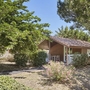 Ein kleiner Bungalow inmitten von Bäumen und Büschen bei Sonnenschein.