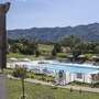 Blick auf einen Pool vor Bergen und Grünflächen bei einer Ferienresidenz.
