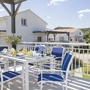 Terrasse mit Esstisch und blauen Stühlen, Blick auf Wohnhäuser und Hügel im Hintergrund.
