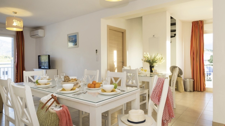 Essbereich einer Ferienwohnung mit gedecktem Tisch und hellen Möbeln.