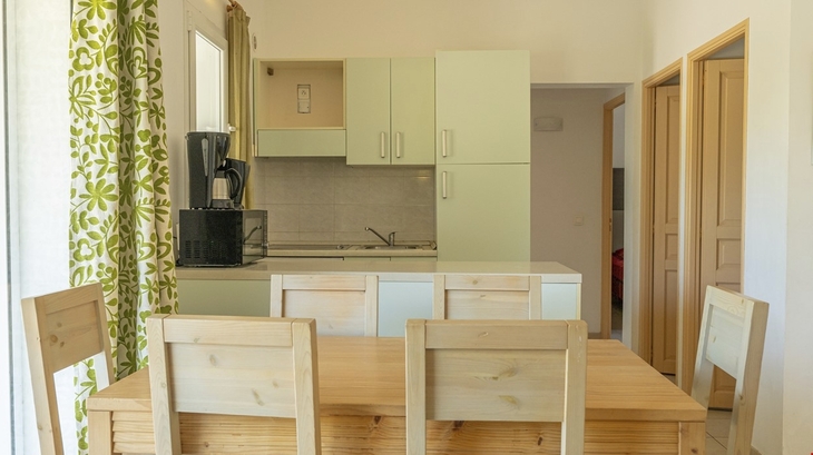 Essbereich mit Holztisch und Küche im Hintergrund.