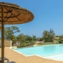 Pool mit Liegestühlen und Sonnenschirmen in einer sonnigen Umgebung