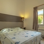 Helles Schlafzimmer mit Doppelbett, Wandlampen und Blick aus dem Fenster ins Freie.
