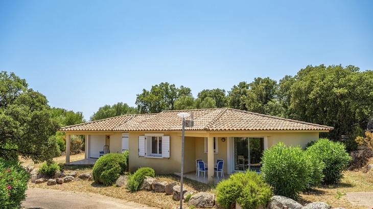 Bungalow mit Garten in ländlicher Umgebung, blauer Himmel im Hintergrund.