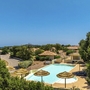 Resort mit Pool und Sonnenschirmen in einer grünen Umgebung.