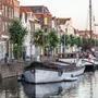 Boote am Kanal vor historischen Gebäuden und einer Windmühle in Rotterdam.