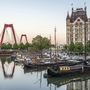 Alter Hafen in Rotterdam mit historischen Schiffen und der roten Brücke im Hintergrund.