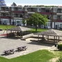 Ferienanlage mit Spielplatz und Bänken vor mehrstöckigen Gebäuden.
