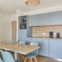 Küche mit blauen Schränken, Esstisch und Stühlen in modernem Apartment.