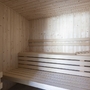 Innenansicht einer modernen, holzverkleideten Sauna mit Sitzbänken.