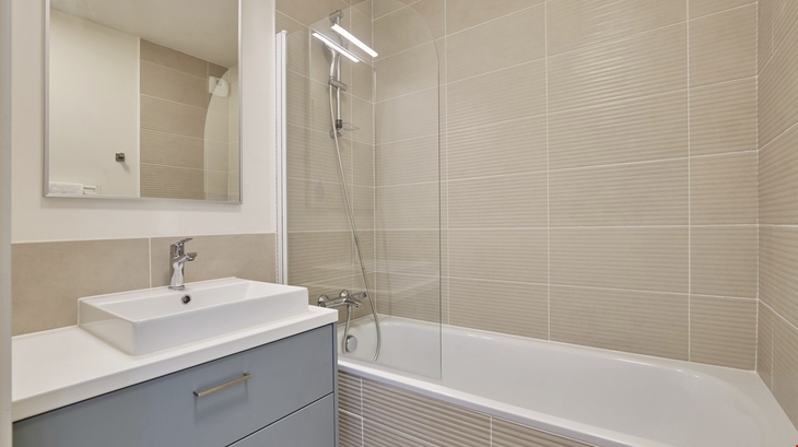 Moderne Badezimmeransicht mit Badewanne, Glasabtrennung und Waschbecken.
