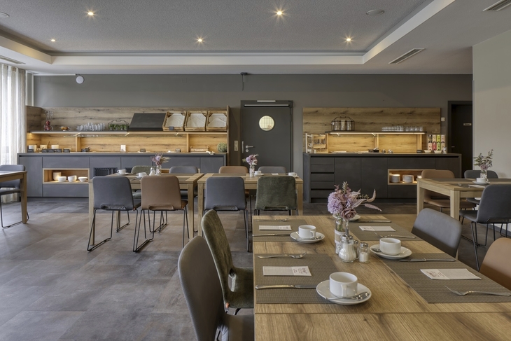 Hotelrestaurant mit gedeckten Tischen und moderner Einrichtung.