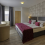 Modernes Hotelzimmer mit Doppelbett, roten Akzenten und Sitzbereich in Gemünden.