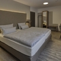 Modernes Hotelzimmer mit Doppelbett und Schreibtisch, dezente Einrichtung.