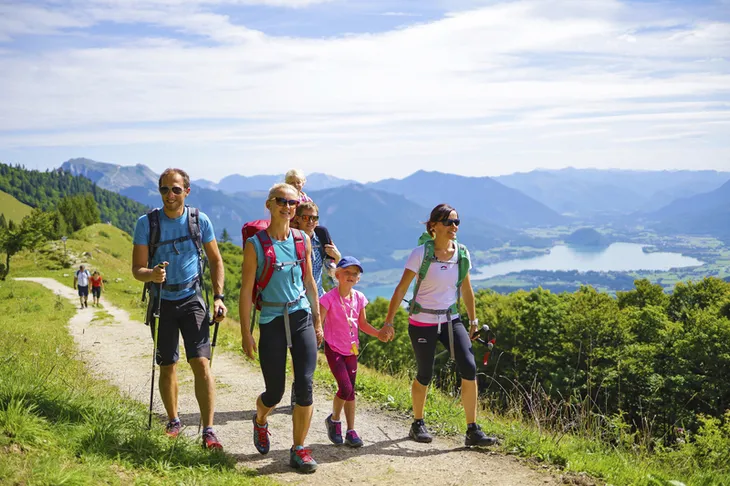 Familie beim Wandern mit Seeblick im Salzkammergut, sonniger Tag, Alpenpanorama.