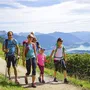 Familie beim Wandern mit Seeblick im Salzkammergut, sonniger Tag, Alpenpanorama.