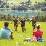 Familie rastet auf Wiese mit See im Hintergrund im Salzkammergut.