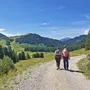 Paar wandert auf einem Weg in einer alpinen Landschaft bei sonnigem Wetter.