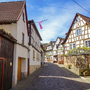 Enge Gasse mit Fachwerkhäusern unter blauem Himmel.