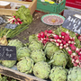 Frisches Gemüse auf einem Marktstand, darunter Radieschen und Artischocken.