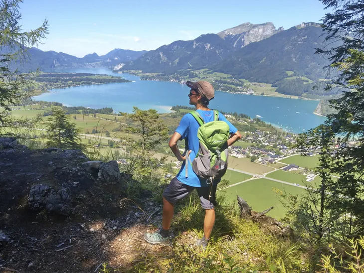 Person beim Wandern mit Blick auf den Wolfgangsee und die umliegenden Berge.